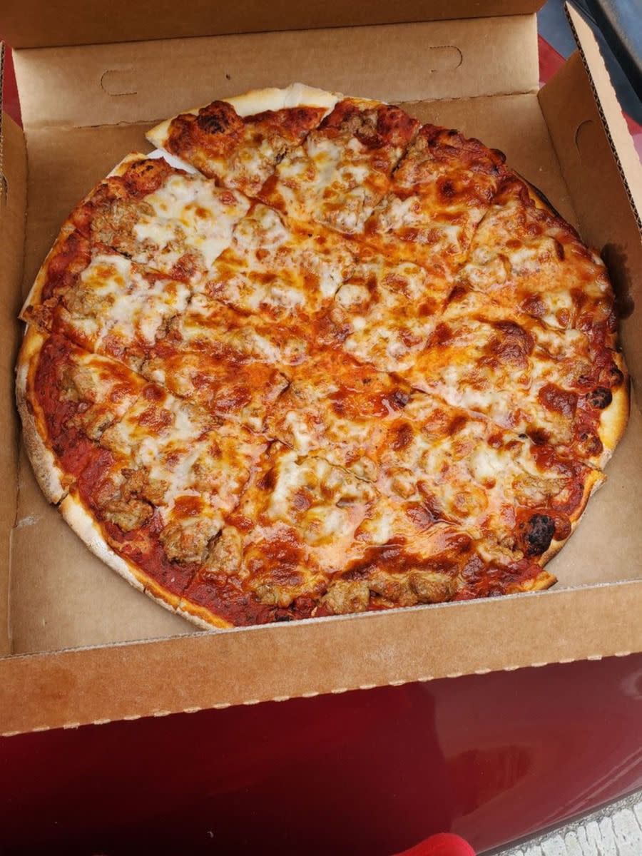 Cheese pizza in box, Marie’s Pizza & Liquors, Chicago, on a red seat