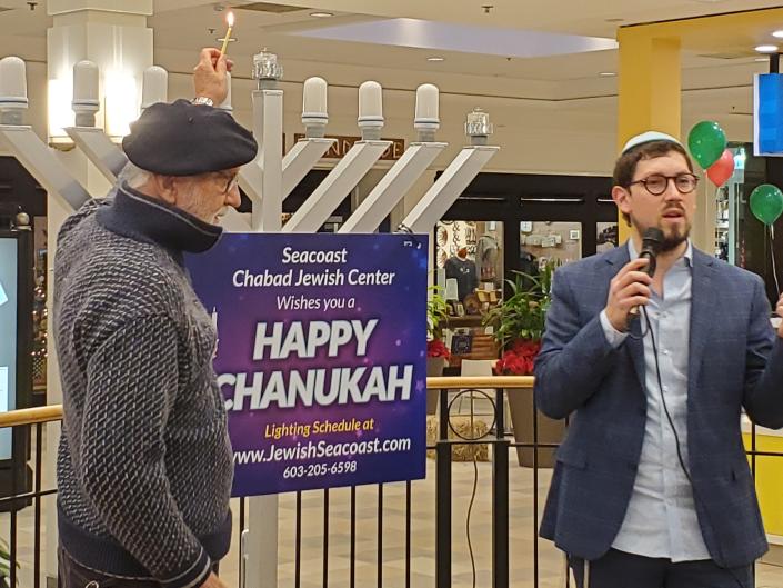 Ken Kowalchek, left, of Hampton, prepares to light the menorah as Rabbi Berel Slavaticki talks about the history and tradition of the Hanukkah ritual at the Mall at Fox Run in Newington Sunday Nov. 28, 2021.