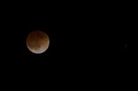 This photo shows the Earth's shadow cast over the surface of the moon as a total lunar eclipse over the Chabot Space and Science Center observatory in Oakland, Calif., Tuesday, April 15, 2014. (AP Photo/Jeff Chiu)