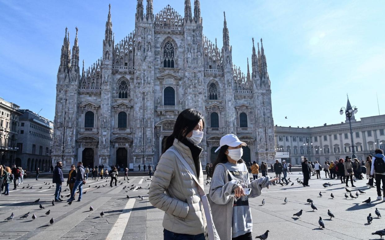 Tourists wear face masks as they walk across the Piazza del Duomo in Milan - Andreas Solaro/AFP