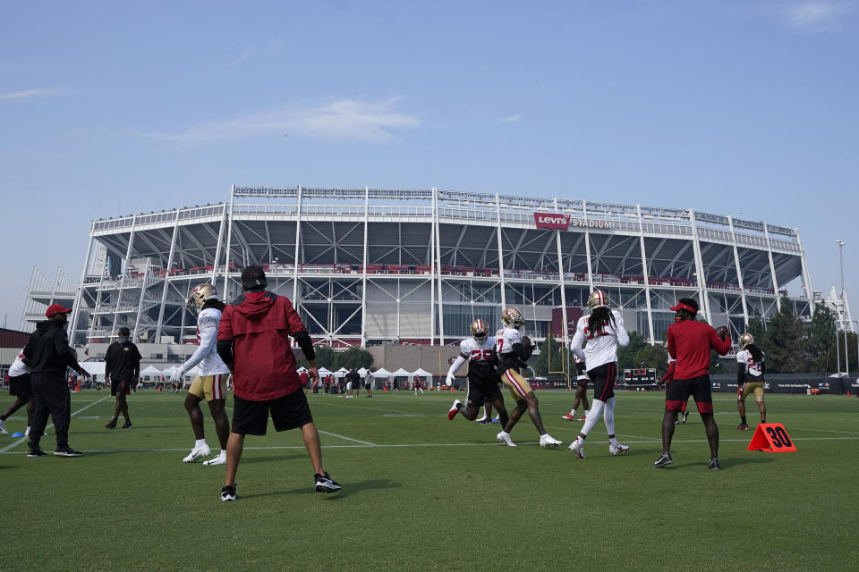 FILE - In this Aug. 22, 2020 file photo, San Francisco 49ers defensive backs run a drill on a field outside of Levi's Stadium during NFL football practice in Santa Clara, Calif. California health officials announced Tuesday, Oct. 20, 2020, that they will allow a limited number of fans to attend professional sporting events in counties with lower rates of transmission of the coronavirus. That includes Santa Clara County, home to the San Francisco 49ers professional football team, but health officials there said they won't allow fans at such events anytime soon. (AP Photo/Jeff Chiu, Pool, File)