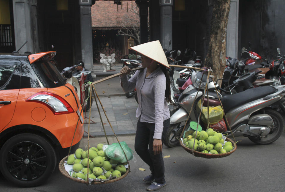 In this Jan. 27, 2014 photo, a street vendor walks by Kim Ngan Temple on Silver Street in the Old Quarter of Hanoi, Vietnam. The 82-hectare (203-acre) area is crammed with Buddhist temples, pagodas and French-colonial shophouses, whose original tiles and peeling yellow paint have become a draw for foreign visitors. It is now among Asia's best-preserved urban hubs of traditional commerce - thanks largely to decades of inattention. (AP Photo/Mike Ives)