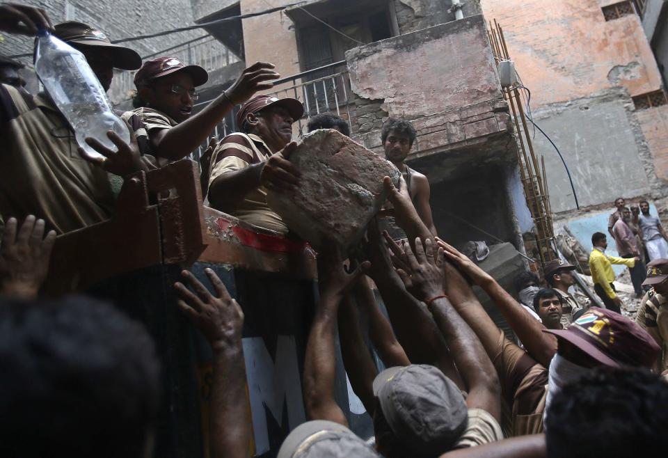 Rescue workers and volunteers load debris onto a truck at the site of a collapsed building in New Delhi