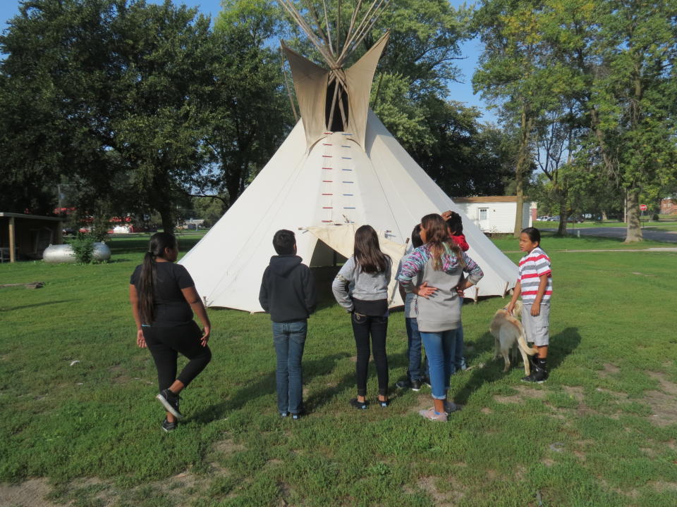 A middle school class from Umonhon Nation Public School, out on a cultural experience in the community, learning about the tipi. 