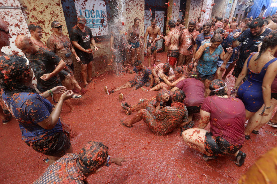 Revellers throw tomatoes at each other during the annual “Tomatina”, tomato fight fiesta, in the village of Bunol near Valencia, Spain, Wednesday, Aug. 30, 2023. Thousands gather in this eastern Spanish town for the annual street tomato battle that leaves the streets and participants drenched in red pulp from 120,000 kilos of tomatoes. (AP Photo/Alberto Saiz)