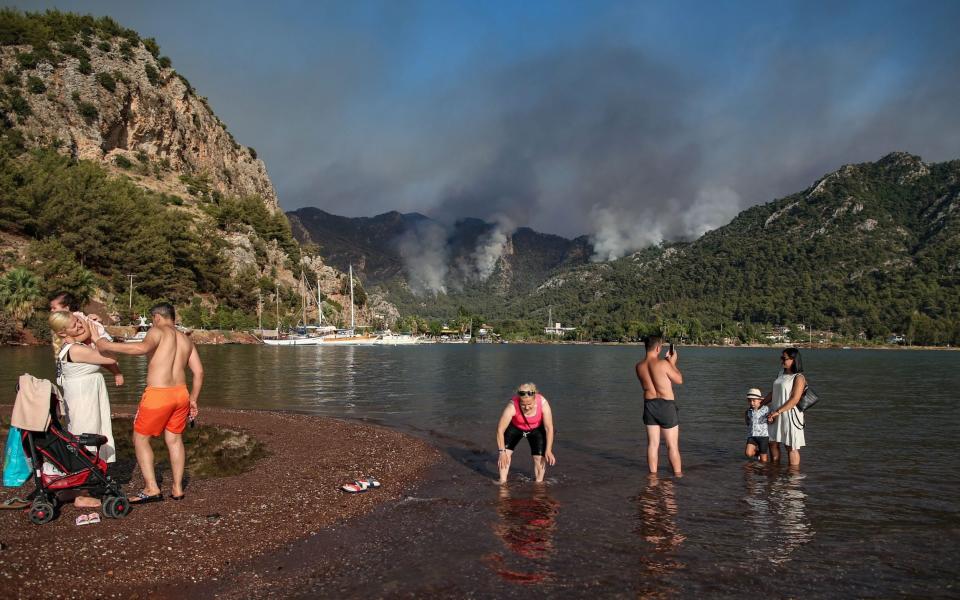 People spend time at the sea backdropped by the wildfires burning in Marmaris - ERDEM SAHIN/EPA-EFE/Shutterstock