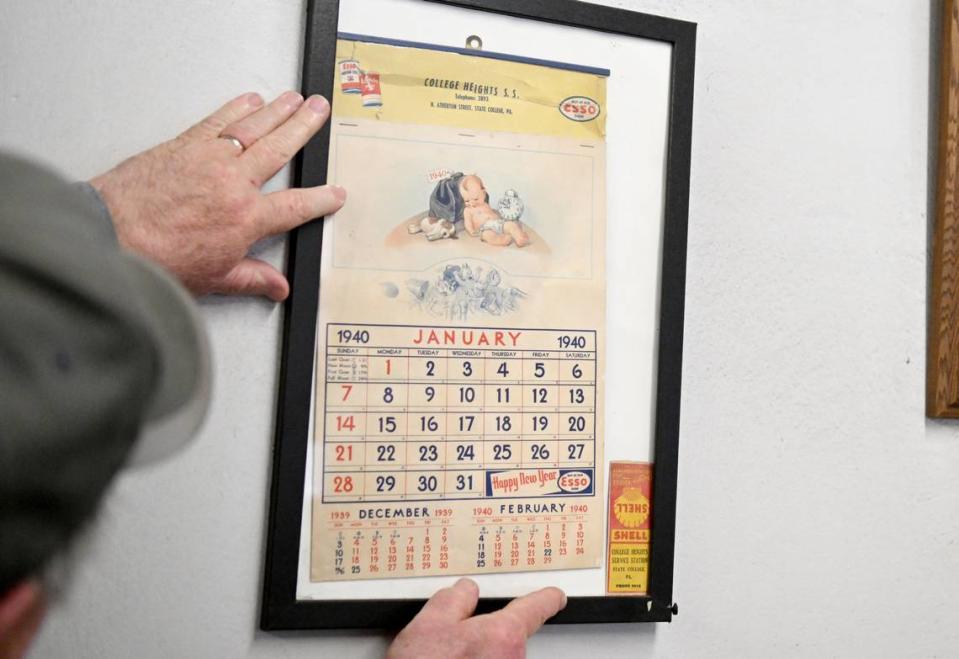 Gary Green adjusts a framed calendar page from 1940 that features the original College Heights Service Station name and a pack of matches from when the service station used Shell. Abby Drey/adrey@centredaily.com