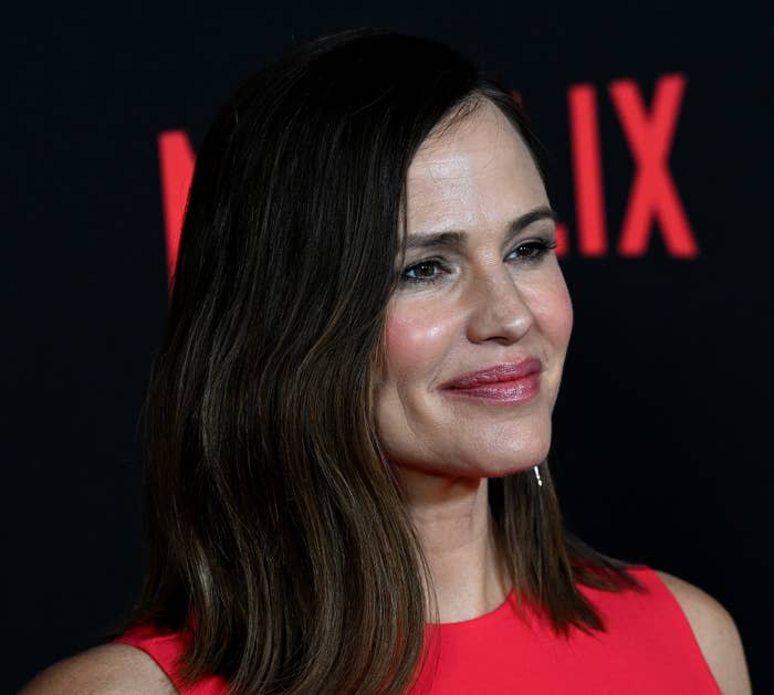 Jennifer Garner smiles in a sleeveless red dress at a Netflix event