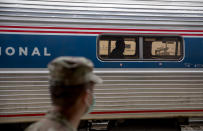 A soldier with the Rhode Island National Guard looks for passengers getting off a train from New York as it arrives Saturday, March 28, 2020, in Westerly, R.I. States are pulling back the welcome mat for travelers from the New York area, which is the epicenter of the country's coronavirus outbreak, and some say at least one state's measures are unconstitutional. Gov. Gina Raimondo ratcheted up the measures announcing she'll also order the state National Guard to go door-to-door in coastal communities starting this weekend to find out whether any of the home's residents have recently arrived from New York and inform them of the quarantine order. (AP Photo/David Goldman)