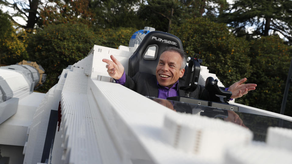 Star Wars actor Warwick Davis poses in the world's largest Lego model of a X Wing fighter at Pinewood studios outside London, Thursday, Sept. 26, 2019. Star Wars talent came together for a global livestream event for the promotion of Triple Force Friday Oct. 4, when new products inspired by the Star Wars franchise are launched worldwide. (AP Photo/Alastair Grant)