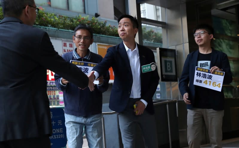 Winning candidate Kelvin Lam and activist Joshua Wong greet people and thank them for their support, outside of South Horizons Station, in Hong Kong