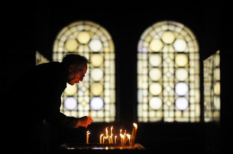 A sexton collects candles during a Christmas mass in the golden-domed Alexander Nevsky cathedral in central Sofia on December 25, 2012