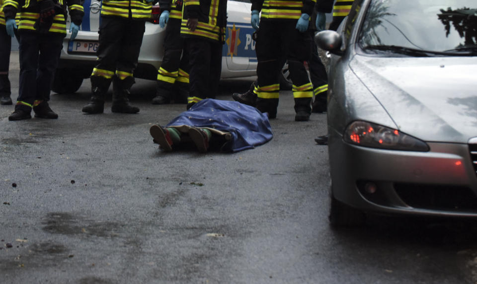 REMOVES SPECIFIC NUMBER OF CASUALTIES AND CLARIFIES SHOOTING DETAILS Firefighters stand by a body on the site of the attack in Cetinje, some 30 km west of Podgorica, Montenegro, Friday, Aug. 12, 2022. A man went on a shooting rampage in the streets of a western Montenegro city Friday, killing multiple people, before being shot dead by a passerby, officials said. (AP Photo/Risto Bozovic)