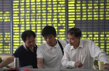 Investors talk in front of an electronic board showing stock information, filled with green figures indicating falling prices, at a brokerage house in Nantong, Jiangsu province, China, July 3, 2015. REUTERS/Stringer