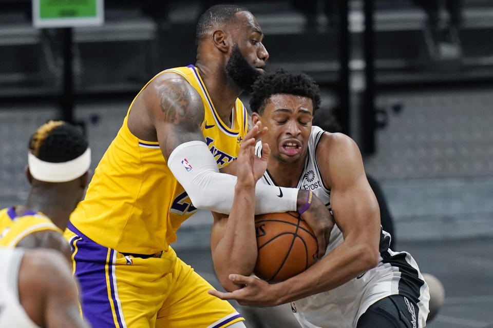 Los Angeles Lakers forward LeBron James, left, and San Antonio Spurs guard Keldon Johnson compete for control of the ball during the second half of an NBA basketball game in San Antonio, Wednesday, Dec. 30, 2020. (AP Photo/Eric Gay)