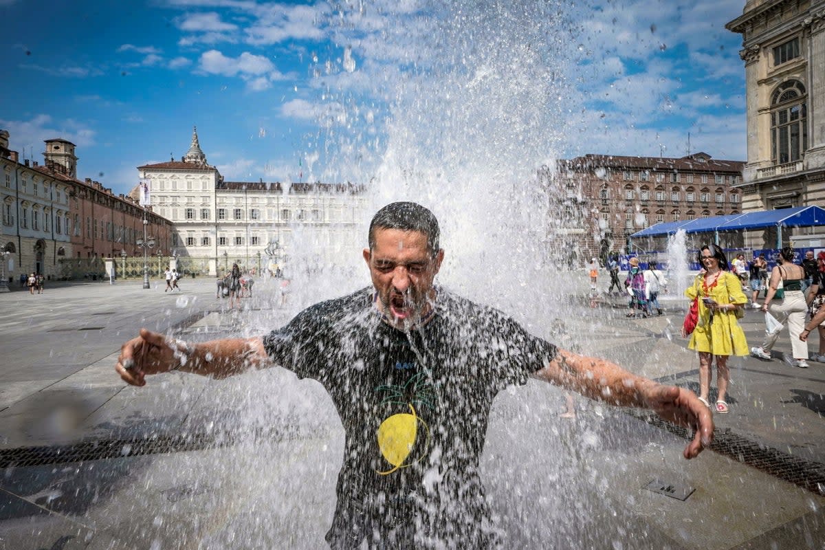 A man cools off in a fountain in Turin, Italy, during the Cerberus heatwave on Saturday  (EPA)