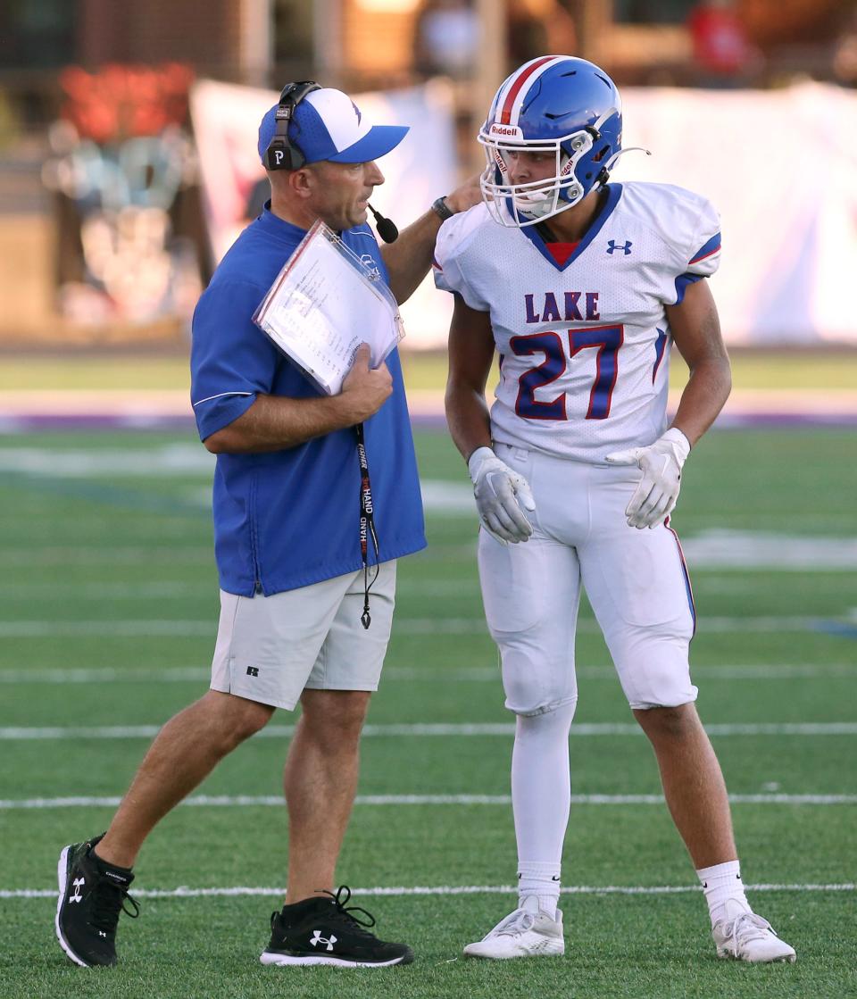 Lake football coach Dan DeGeorge speaks with Josh Sedmock (27) during the Blue Streaks' 41-14 win against Alliance at Kehres Stadium on Friday, August 19, 2022.