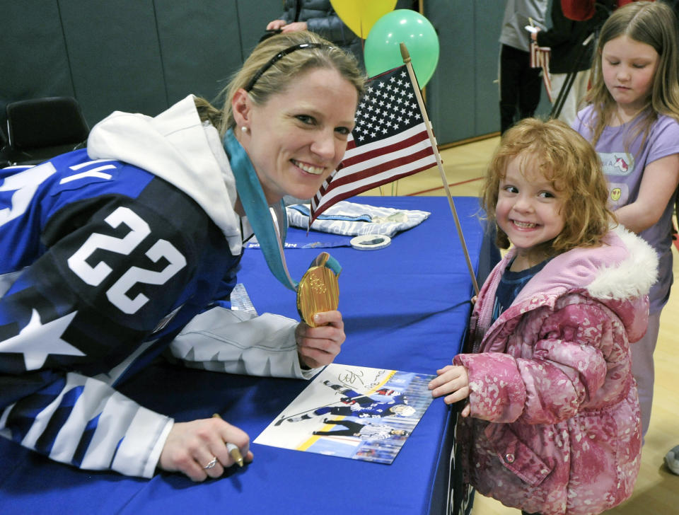 FILE - Olympic gold medalist Kacey Bellamy poses for a photo with Addie Raymond, 4, of Westfield, Mass., during a meet and greet reception at the Boys & Girls Club of Greater Westfield, in Bellamy's hometown of Westfield, Mass., in this Saturday, March 10, 2018, file photo. Three-time U.S. Olympian Kacey Bellamy is retiring a month after the women's world hockey championships were postponed. Bellamy, who turned 34 in April, announced her decision Tuesday, May 18, 2021, to retire after 15 years with the U.S. women's national team. (Frederick Gore/The Republican via AP, File)