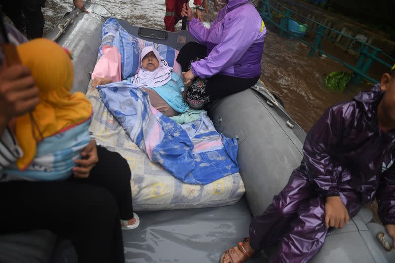 An elderly woman is being evacuated on an inflatable boat by a rescue team, after floods hit a residential area in Depok, south of Jakarta