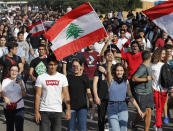 Student protesters wave their national flags and shout slogans, as they protest against the government in front of the education ministry in Beirut, Lebanon, Friday, Nov. 8, 2019. Lebanese protesters are rallying outside state institutions and ministries to keep up the pressure on officials to form a new government to deal with the country's economic crisis. (AP Photo/Hussein Malla)