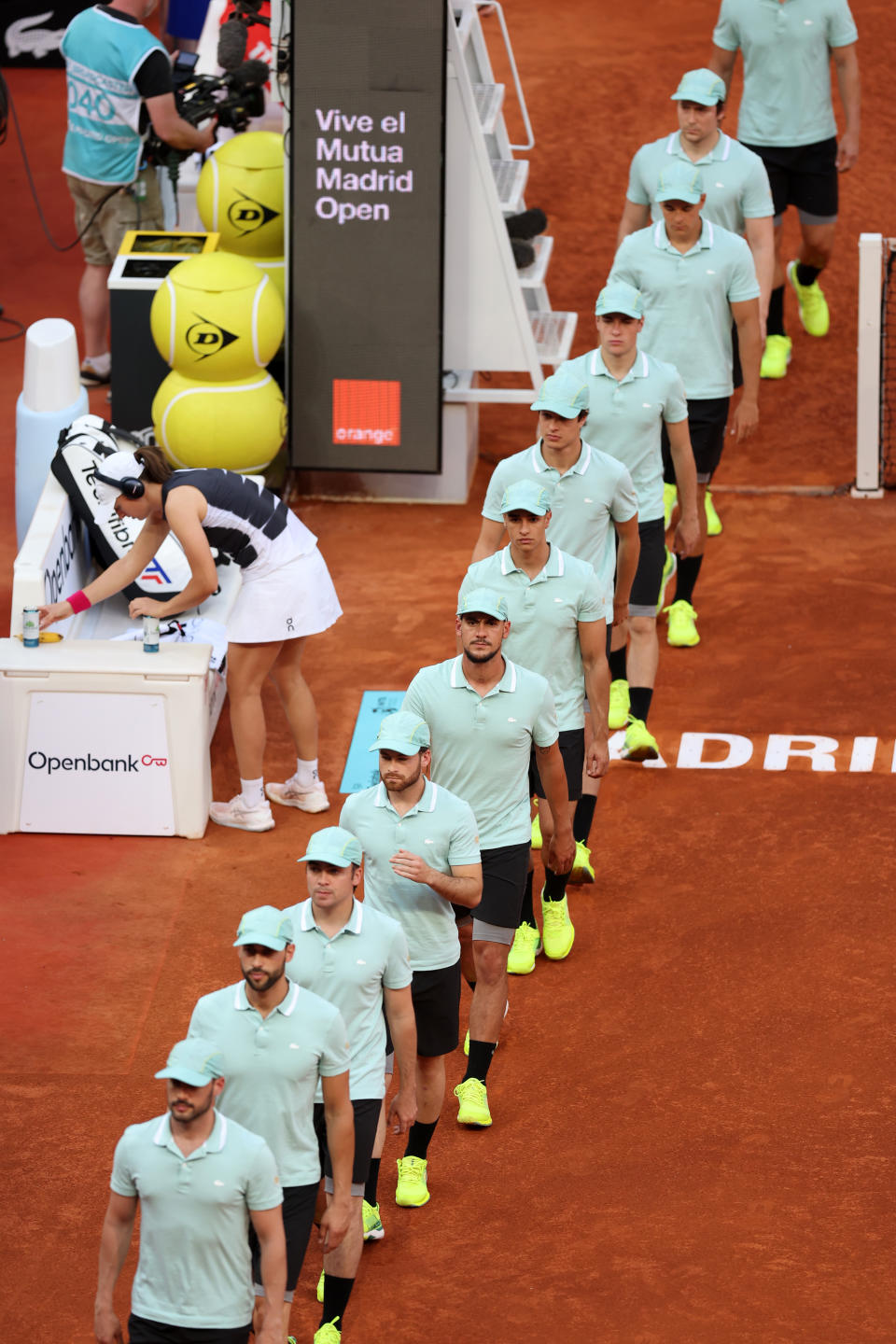 Iga Swiatek gets ready for her match as the ball men walk past her.