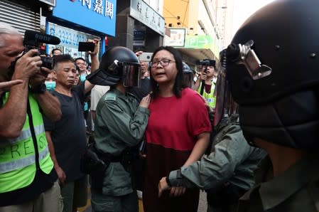 Police officers escort a woman near Amoy Plaza shopping mall in Kowloon Bay, Hong Kong