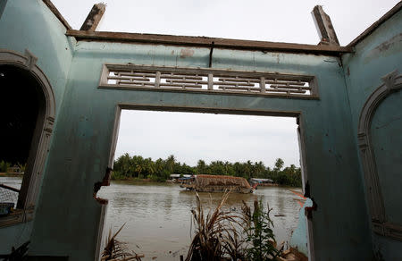 A boat transports coconuts past a collapsed house damaged by landslide along Mekong river in Mo Cay town, Vietnam December 18, 2018. Picture taken December 18, 2018. REUTERS/Kham