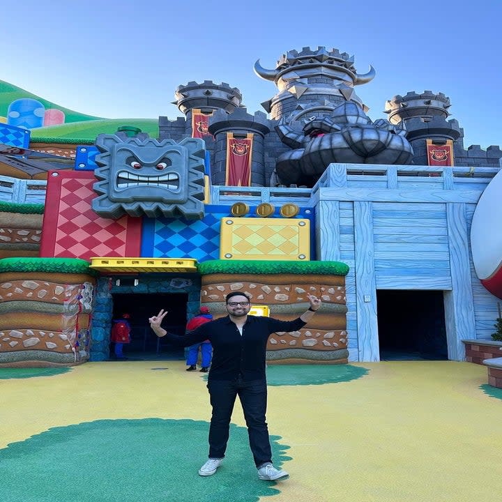 Brian smiling and giving the peace sign while standing in front of Super Nintendo World