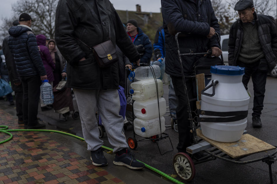 Residents queue to fill containers with drinking water in Kherson, southern Ukraine, Sunday, Nov. 20, 2022. Russian forces fired tank shells, rockets and other artillery on the city of Kherson, which was recently liberated from Ukrainian forces. (AP Photo/Bernat Armangue)