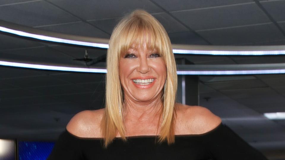 suzanne somers standing with her hands on her hips and smiling for a photo