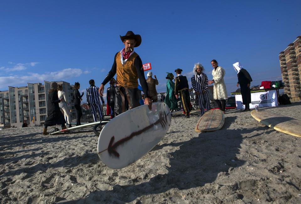 A participant carries his board before the third annual Rockaway Halloween surf competition at Rockaway Beach in the Queens borough of New York