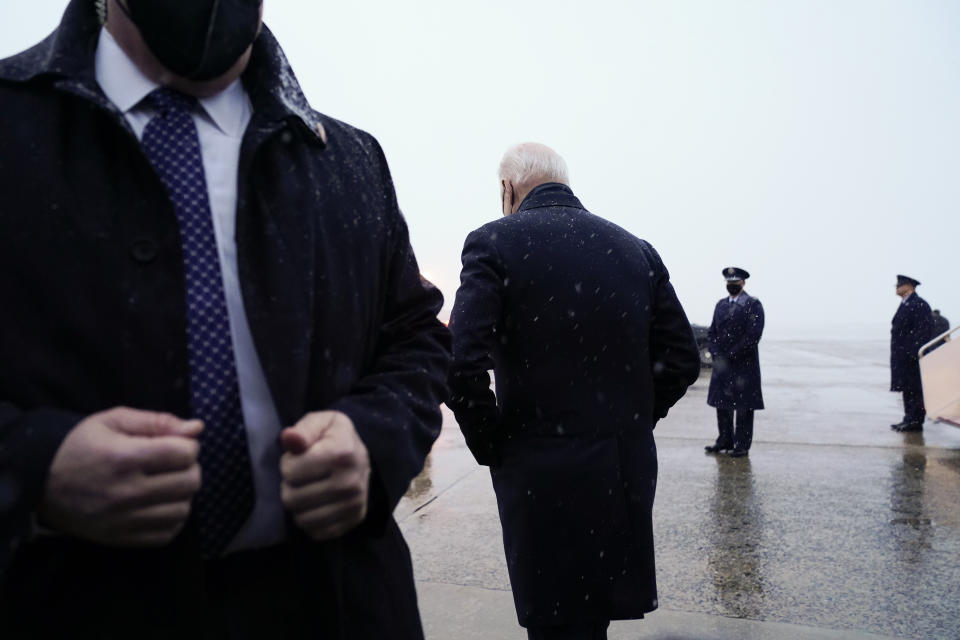 El presidente de Estados Unidos, Joe Biden (al centro, de espaldas) camina hacia su caravana de autos después de hablar con los periodistas en la Base Andrews de la Fuerza Aérea, en Maryland, el 28 de enero de 2022. (AP Foto/Andrew Harnik)