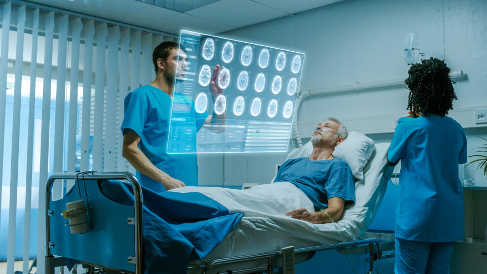 Doctor looking at augmented reality screen with a patient on a bed in the background.