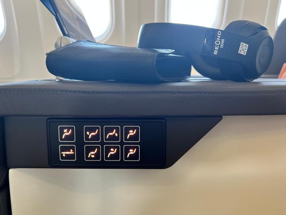 Eight black buttons with orange LEDs on the armrest of a seat on Beond A319 show various options to adjust the seat.