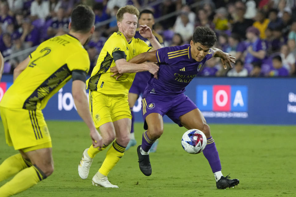 Orlando City's Ramiro Enrique, right, moves the ball past Nashville SC's Dax McCarty, center, and Daniel Lovitz (2) during the second half of an MLS soccer match, Saturday, April 1, 2023, in Orlando, Fla. (AP Photo/John Raoux)