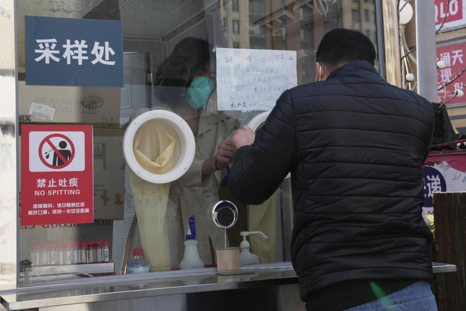 Workers adjust the glove ports at a nuclei test station in Beijing, China, Tuesday, Jan. 18, 2022. The first reported case of the omicron variant has prompted stepped-up measures in Beijing, just weeks before it hosts the Winter Olympic Games. (AP Photo/Ng Han Guan)