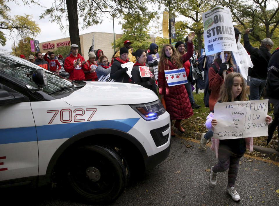 Dozens of Chicago Teachers Union members, CPS students and supporters march around a police car blocking the street and continue to march through the streets of Chicago's Hyde Park neighborhood during the "Nurse in Every School" Solidarity March for Justice on Monday, Oct. 21, 2019. (Antonio Perez/Chicago Tribune via AP)