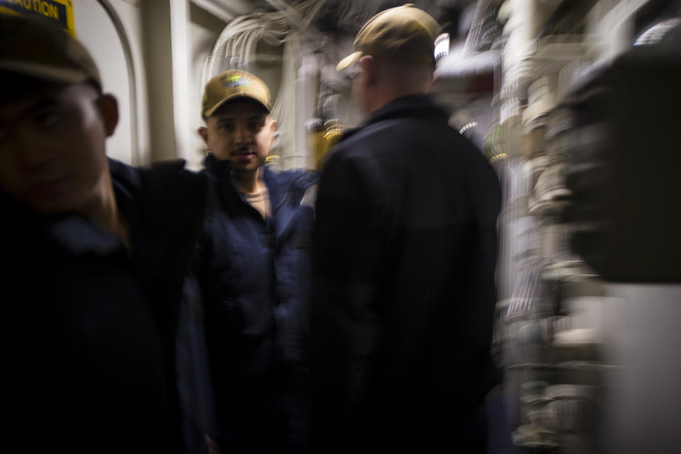 Navy Chaplain Lt. Cmdr. Ben Garrett, right, makes his way through the tight corridors within the USS Bataan on Monday, March 20, 2023 at Norfolk Naval Station in Norfolk, Va. The corridors on Navy ships are about 3 feet wide which made life on the ship more difficult during the COVID-19 pandemic. (AP Photo/John C. Clark)