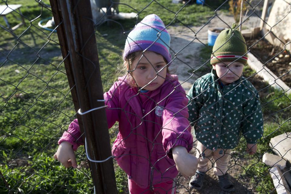 In this photo taken Thursday March 27, 2014, Crimea's Tatar Sedomed Setumerov's children, Diana, 4, left, and Enver, look through a wire fence in the yard of their recent squatter settlement in Lozovoye-2 not far from Simferopol, Crimea. On Saturday the Crimean Tatar Qurultay, a religious congress will determine whether the Tatars will accept Russian citizenship and the political system that comes with it, or remain Ukrainian citizens on Russian soil. (AP Photo/Pavel Golovkin)