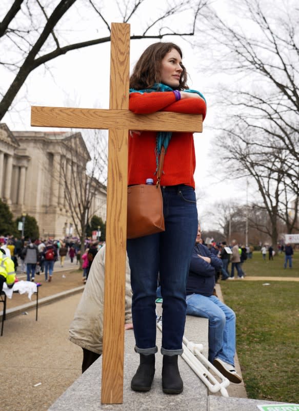 A participant stands with a large wooden cross in front of the U.S. Supreme Court at the 47th annual March for Life in Washington