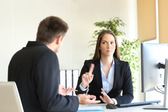 A woman looks stern in conversation with a man.