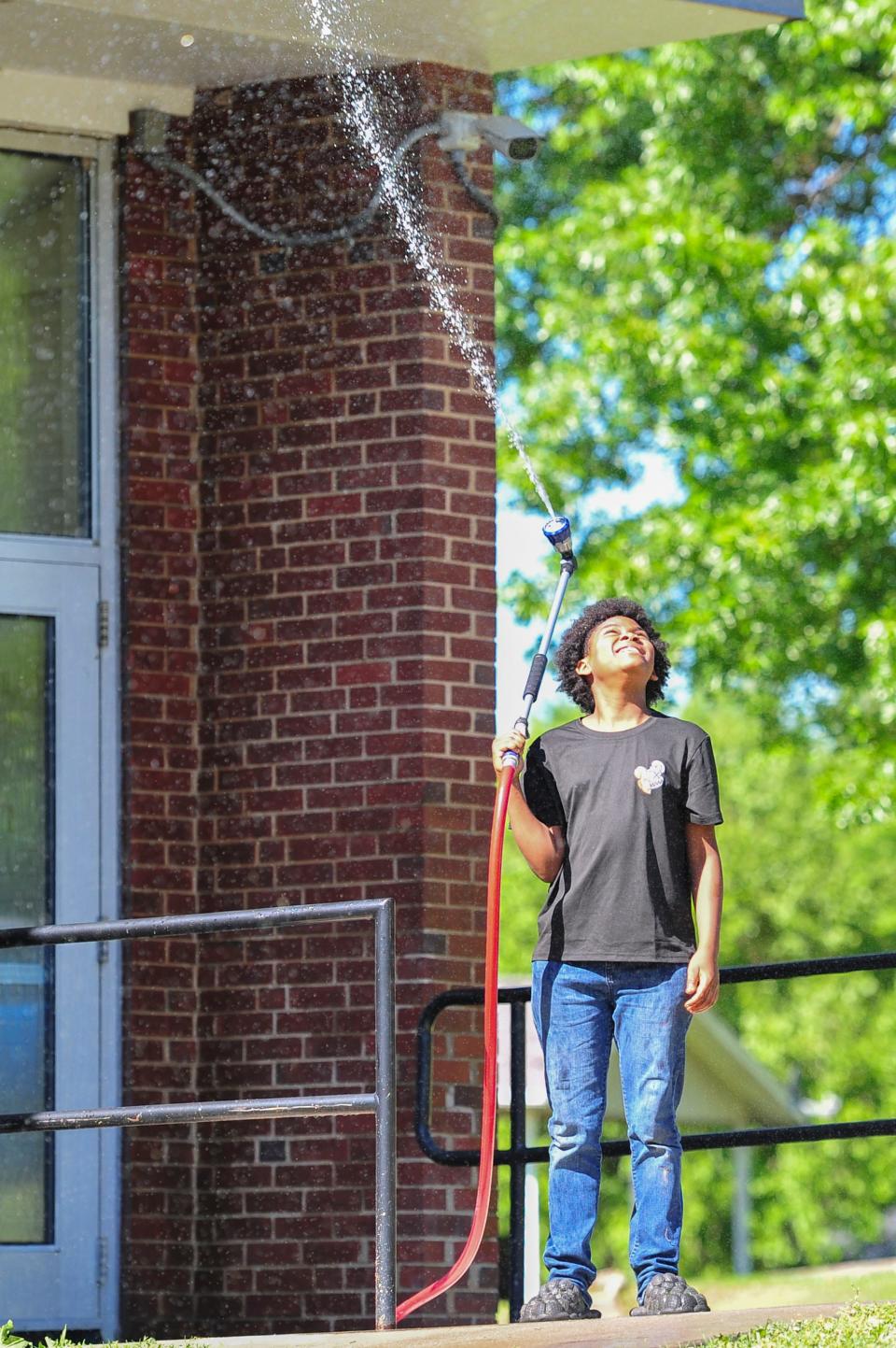 Sixth grader Deondre Jacobs plays with the hose after school in garden club at Vine Middle School on Wednesday, May 1, 2024.