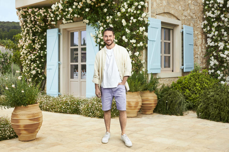 Craig posing in front of a Greek house with blue shutters.