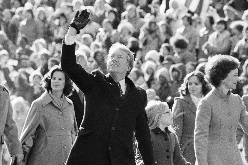 President Jimmy Carter waves to the crowd while walking with his wife, Rosalynn, and their daughter, Amy, along Pennsylvania Avenue from the Capitol to the White House following his inauguration in Washington, Jan. 20, 1977. (AP Photo/Suzanne Vlamis)