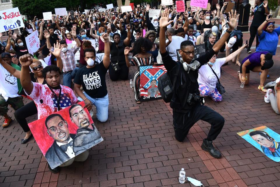 Protesters take a knee and pause for a moment of silence on Main Street in downtown Greenville during a protest of the death of George Floyd, Sunday, May 31, 2020.