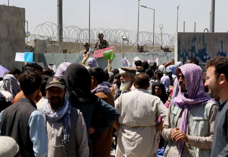 Crowds of people show their documents to U.S. troops outside the airport in Kabul