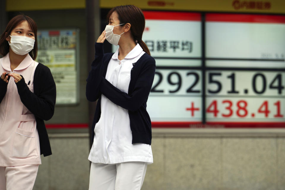 Women wearing protective masks walk in front of an electronic stock board showing Japan's Nikkei 225 index at a securities firm Thursday, May 6, 2021, in Tokyo. Asian shares were mixed Thursday on cautious optimism about upcoming company earnings reports showing some recovery from the damage of the coronavirus pandemic. (AP Photo/Eugene Hoshiko)