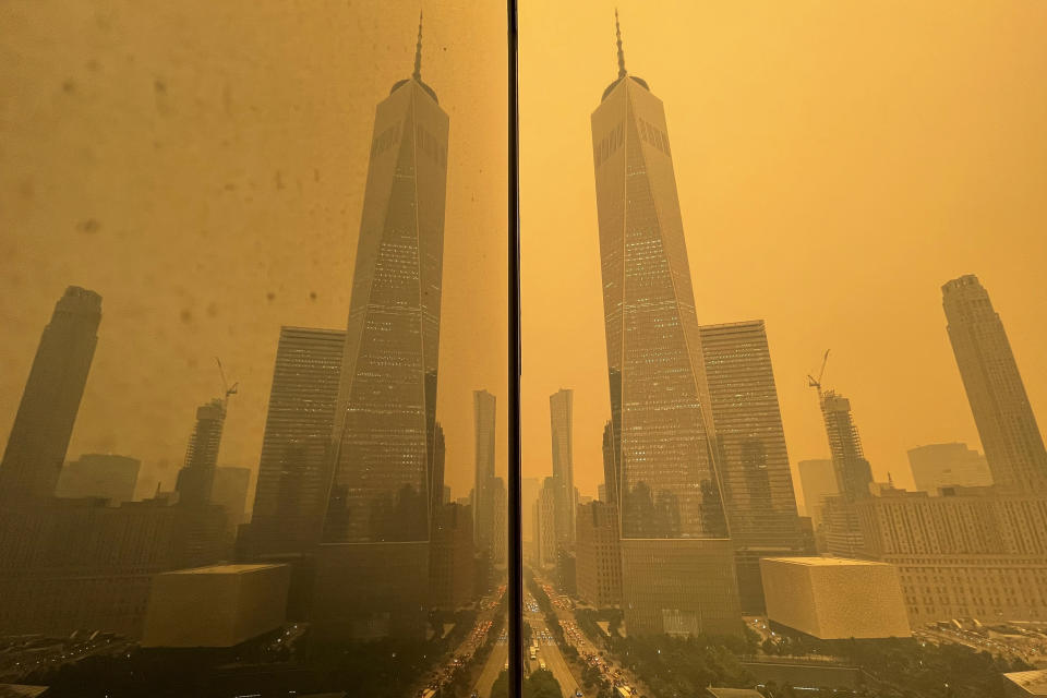 Traffic in New York moves along West Street past One World Trade Center, in this mirror image reflected in the facade of a building on June 7, 2023. The smokey haze was caused by wildfires in Canada. (AP Photo/Andy Bao)