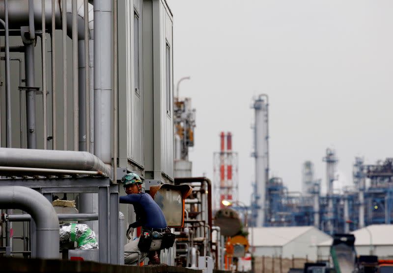FILE PHOTO:A worker is seen in front of facilities and chimneys of factories at the Keihin Industrial Zone in Kawasaki