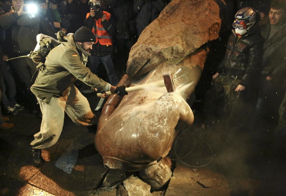 A man holds a sledgehammer as he smashes a statue of Soviet state founder Vladimir Lenin, which was toppled by protesters during a rally organized by supporters of EU integration in Kiev, December 8, 2013. Crowds toppled a statue of Soviet state founder Vladimir Lenin in the Ukrainian capital and attacked it with hammers on Sunday in the latest mass protests against President Viktor Yanukovich and his plans for closer ties with Russia. REUTERS/Maxim Zmeyev (UKRAINE - Tags: POLITICS CIVIL UNREST)